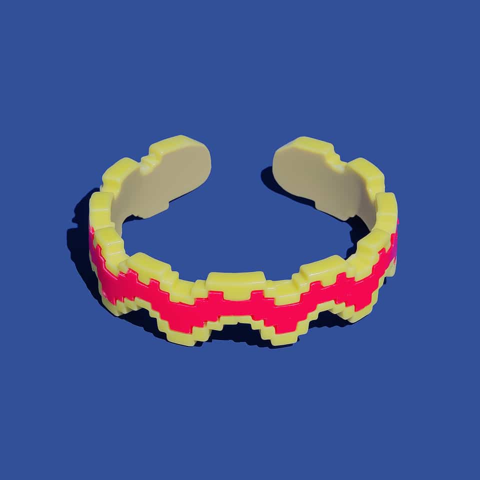 Open polymer clay cuff bracelet shaped as a stepped pixel zigzag band in pale lemon yellow, with a neon pink stripe down the middle, a one-square yellow edge on both sides and two…