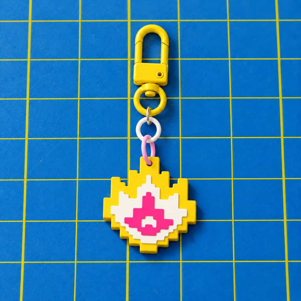 A layered Pixel Flame charm hanging from a snap clasp.