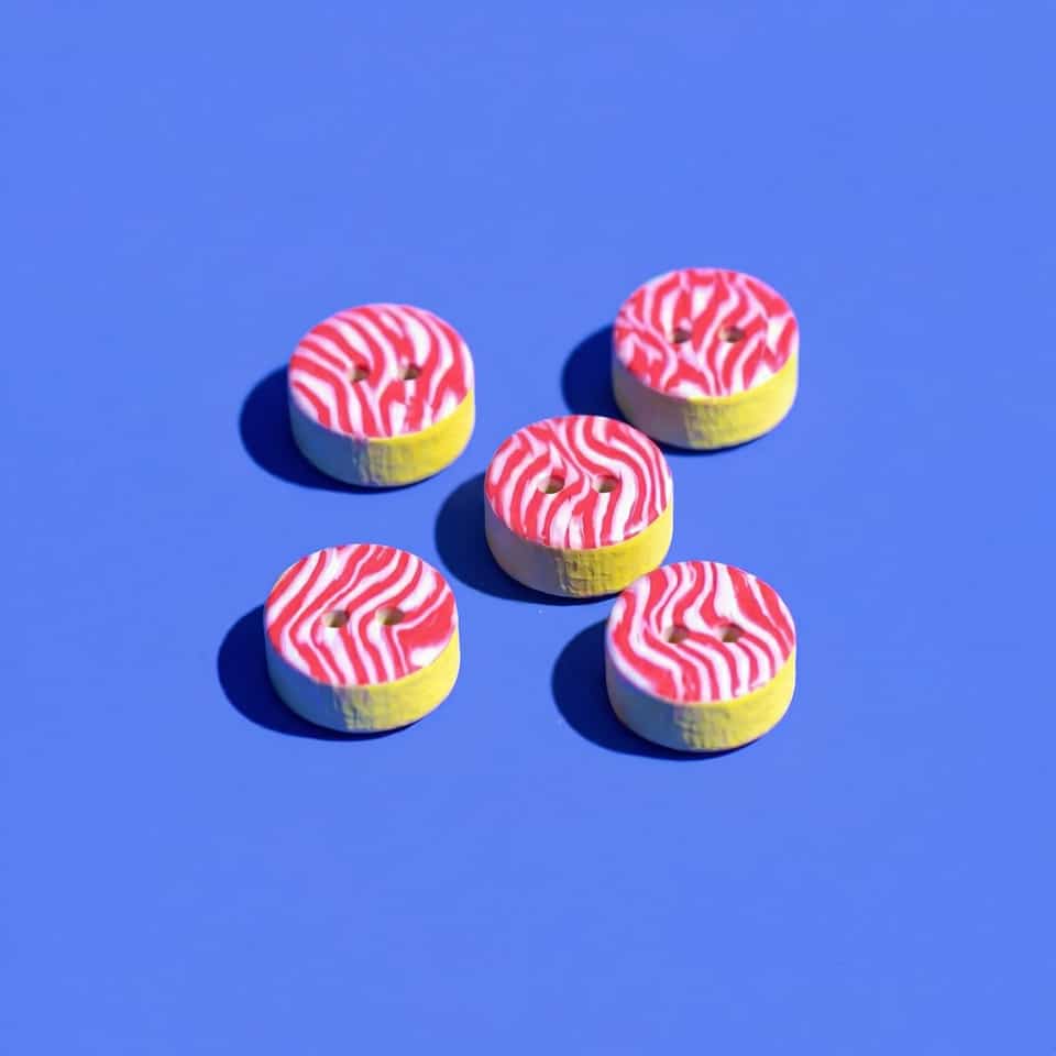 Polymer Clay Coral-Pink & White Wavy Buttons. Button made with cane slice with a sanded buffed finish. Build a wavy red-and-white striped cane or slab face, cap it on a pale-yello…