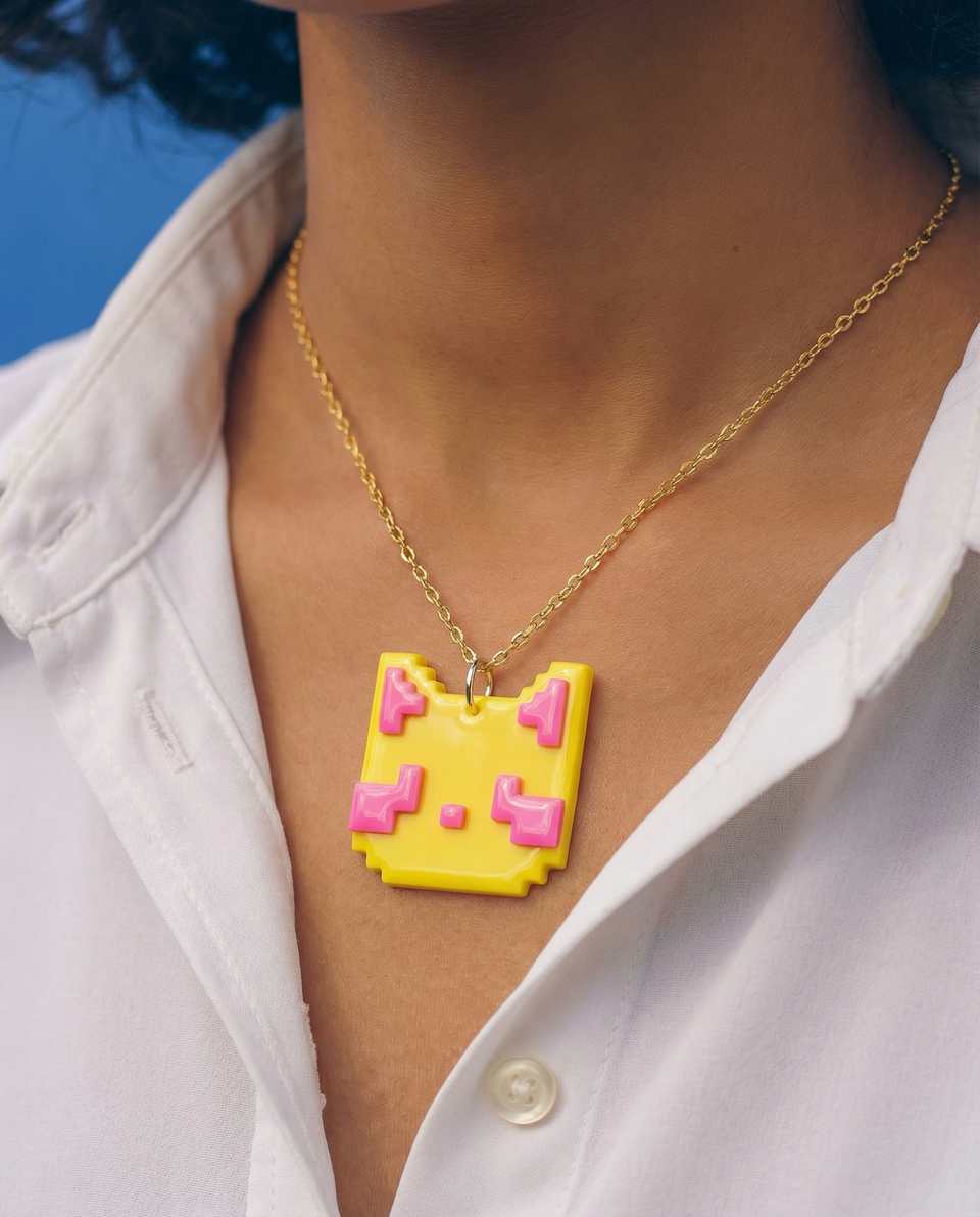 Yellow and hot pink pixel cat tile worn as a necklace pendant