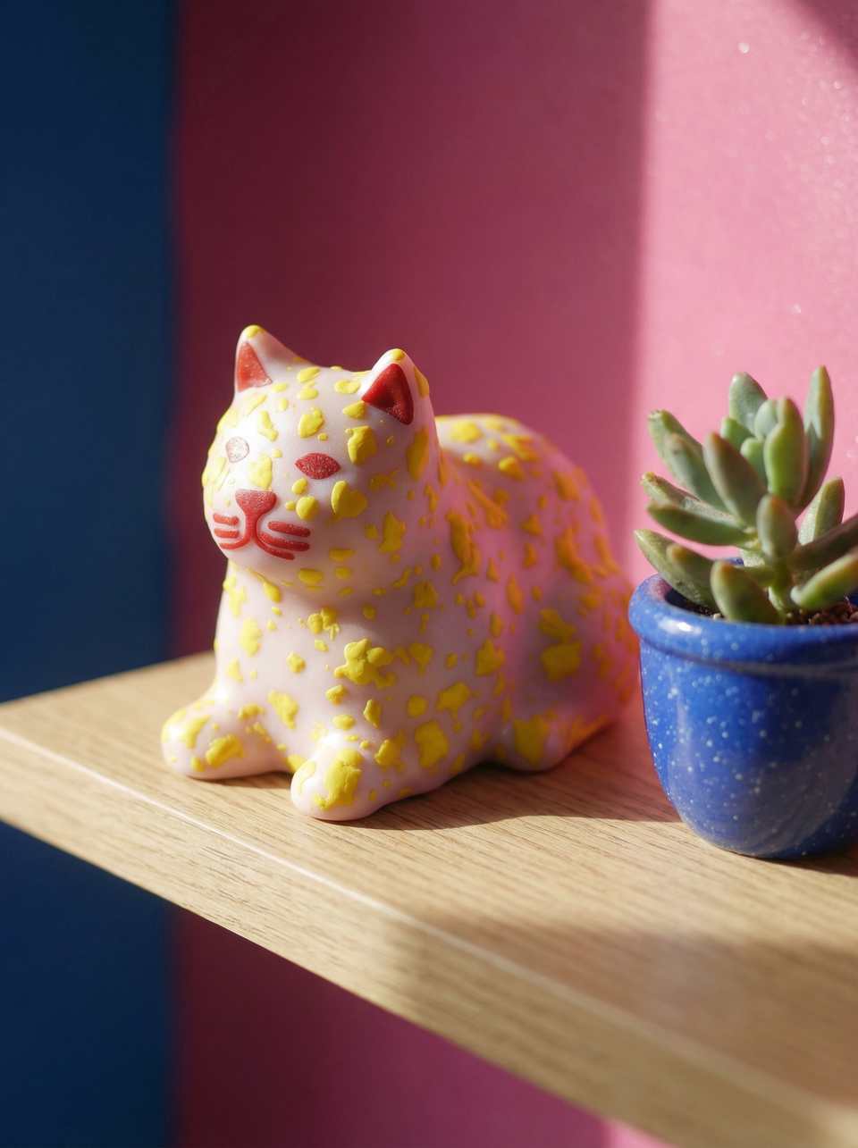 Pink terrazzo loaf cat figurine on wooden shelf with blue and pink walls